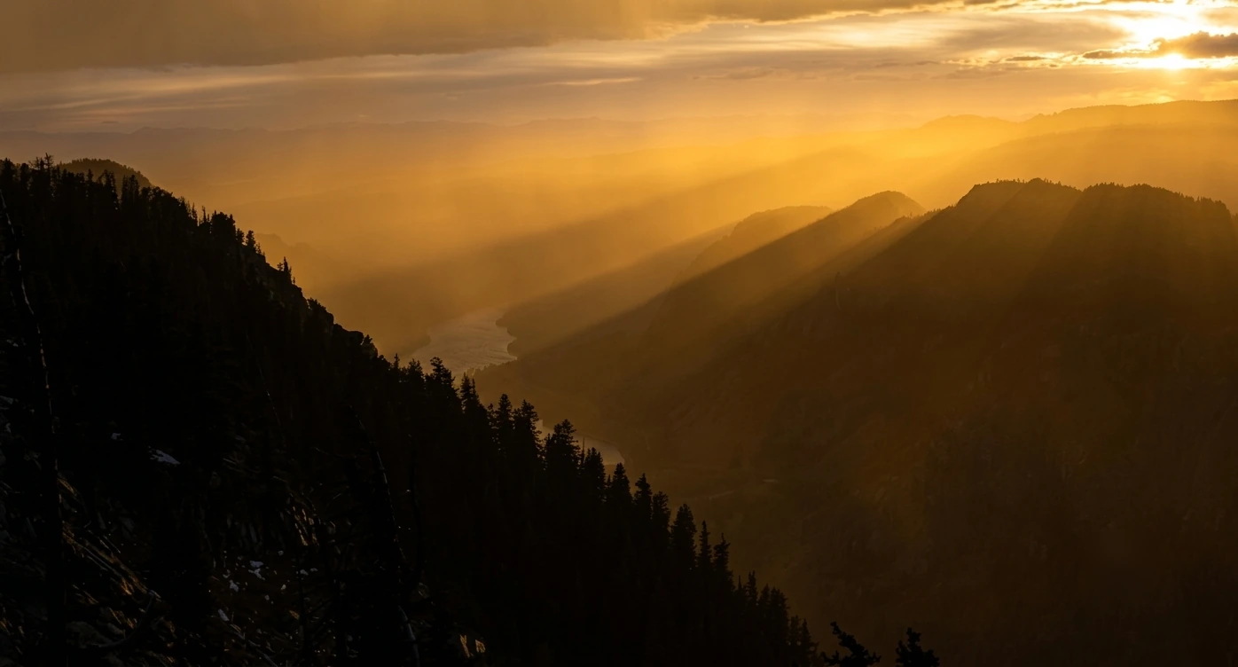 Golden sunrays over a layered mountain valley at sunset
